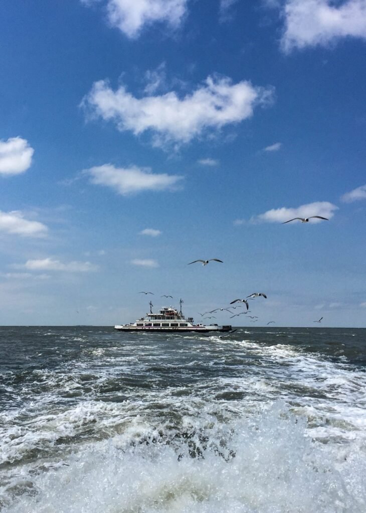 The Ocracoke ferry seen across open water with gulls overhead as it makes the crossing.