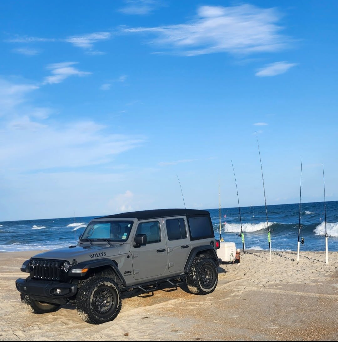 Jeep Wrangler Willys rental on the Outer Banks beach with five surf rods in the spikes